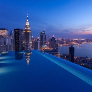 Luxuriöses Hotel mit Infinity-Pool und Skyline-Blick bei Nacht.